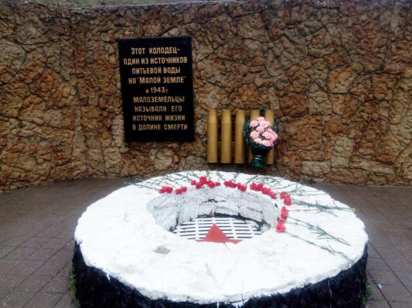 Памятник «Колодец жизни» с возложенными цветами в Новороссийске
